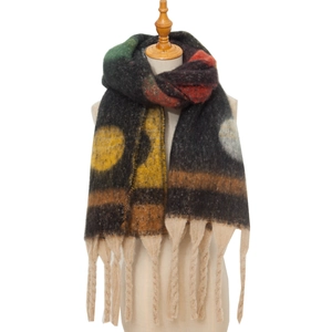 Close-up of thick knitted scarf with jacquard dots and long tassels in retro colors
