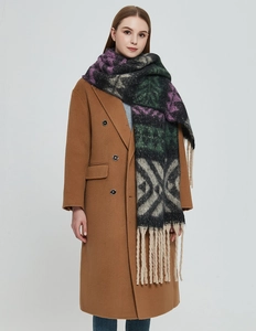 Détail d'une écharpe épaisse en jacquard avec franges colorées sur un manteau marron