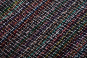 Close-up of multicolor tweed fabric showing intricate mixed yarn weave and texture