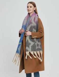 Detail eines dicken Strickschals mit Sternenmuster und langen Fransen am Modell