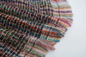 Macro shot of colorful tweed fabric with fringe details and woven texture