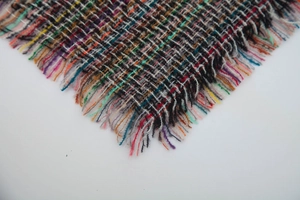 Detailed macro view of colorful woven fabric with natural fringe edges for winter scarf