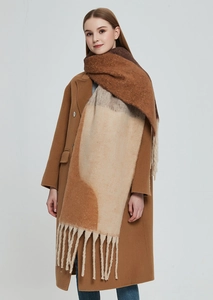 Detailed view of thick knit scarf with chunky fringe and geometric earth tone pattern