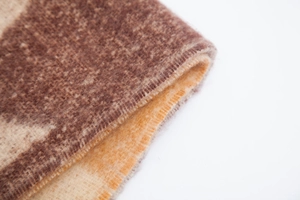 Nahaufnahme des dicken beige-braun gesprenkelten Jacquard-Schals mit weicher Plüsch-Textur