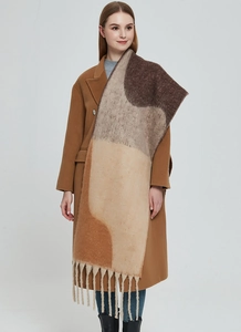 Detail of thick knit scarf with long fringe and geometric brown patchwork pattern