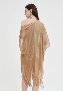 Detail of champagne gold mesh shawl featuring metallic texture and long fringe hem