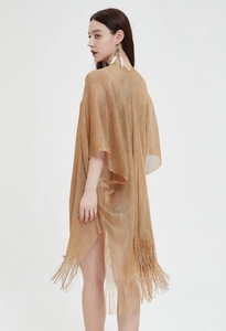 Detail of gold hollow knit shawl featuring elegant fringe hem and metallic texture