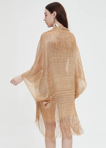 Close-up of golden mesh knit shawl featuring intricate cut-outs and long fringe tassels