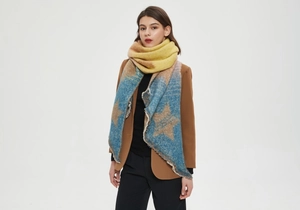 Detail of star pattern knit scarf with blue yellow brown gradient and fringe edges