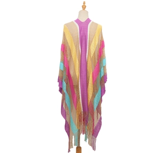 Close-up of crochet hollow out poncho with vibrant rainbow stripes and long fringe tassels