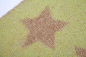 Macro shot of fluffy yellow knit scarf fabric with light brown star pattern texture