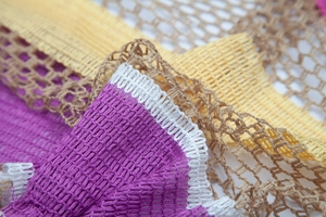 Close-up of rainbow striped mesh knit shawl showing purple edge and woven texture