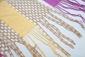 Close-up of rainbow striped knit shawl showing hollow mesh texture and long tassels