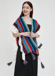 Dettaglio dello scialle in maglia boho con motivi a zigzag, volant e nappe colorate
