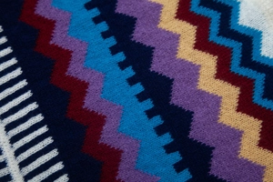 Dettaglio del tessuto a maglia con motivi a zigzag blu scuro, rosso e giallo