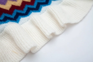 Dettaglio macro della trama a zigzag multicolore con polsini a coste bianche