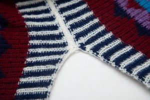 Dettaglio delle cuciture e della trama a maglia a righe multicolore di questo poncho