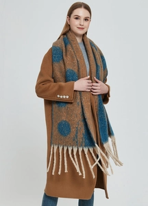 Detail of thick chunky knit scarf featuring navy blue polka dots and cream tassels