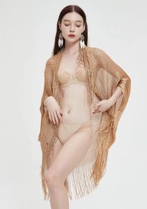 Detailed view of shimmering gold knit shawl featuring long fringe trim and metallic texture