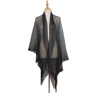 Detail of black openwork lace shawl featuring delicate knit mesh and long flowing tassels