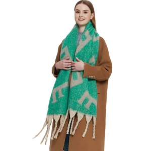 Détails de la texture du fil bouclé épais et des longues franges tressées sur l'écharpe verte