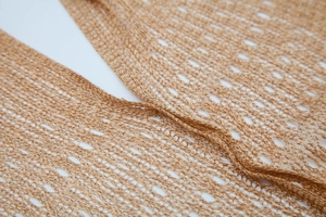 Close-up of light brown hollow knit fabric showing breathable mesh texture and weave detail