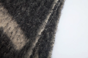 Gros plan d'une écharpe épaisse en fil bouclé avec motif patchwork gris et beige camel