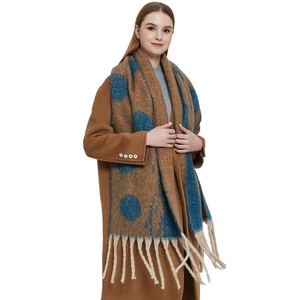Thick winter scarf with blue polka dots and long tassels on brown knit fabric