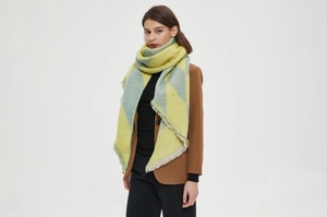 Detail of soft fringe and textured plaid pattern on a thick yellow and grey shawl