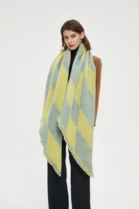 Detail view of yellow and blue argyle knit shawl with frayed tassel edges and soft texture