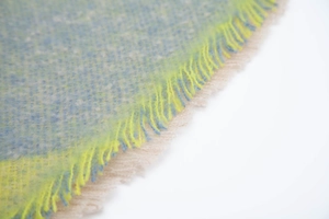 Detailed macro view of the knitted shawl with yellow blue patterns and beige tassels