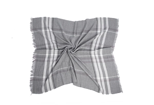 Detail of grey and white plaid scarf featuring woven fabric and fine tassel edges