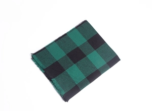 Gros plan sur la texture du foulard à carreaux vert et noir avec détails de franges