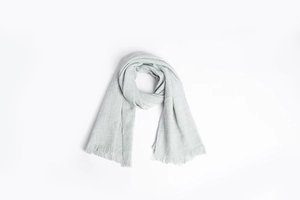 Détail d'une écharpe longue en maille gris clair avec texture douce et franges fines