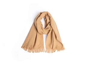 Gros plan d'une écharpe en maille marron camel avec franges et texture douce