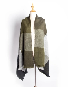Détail d'une écharpe à carreaux vert et gris avec franges douces sur mannequin en bois