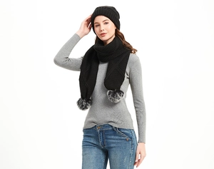 Detail von schwarzem Strickset mit Rautenmuster, Beanie und Schal mit grauen Kunstfellbommeln