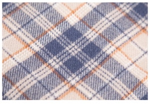 Close-up of thick plaid scarf fabric in navy, cream and orange with soft texture