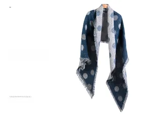 Dettaglio di sciarpa in maglia spessa con motivi a pois blu scuro e grigio con frange