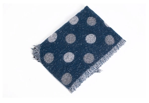 Dettaglio di sciarpa spessa blu scuro a pois bianchi con bordi sfrangiati e nappe