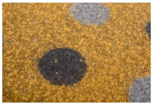 Dettaglio macro del tessuto a maglia gialla spessa con pois grigi e trama morbida