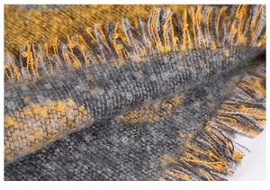 Dettaglio della sciarpa a quadri grigio e giallo in maglia spessa con frange morbide