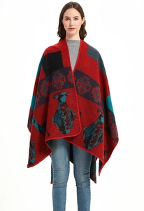 Detail of red geometric knit poncho with Christmas deer pattern and finished edges