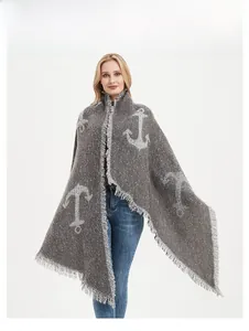 Close-up of thick grey knit shawl featuring white anchor pattern and fringe detail