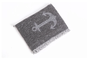 Close-up of dark grey knit scarf featuring a shimmering silver anchor motif and fringe detail