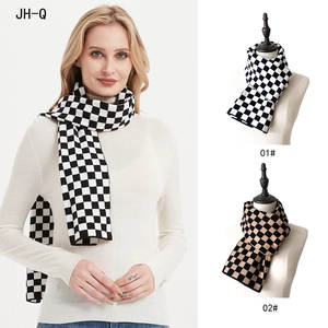 Detail view of thick checkerboard knitted scarf in classic black, white and khaki patterns