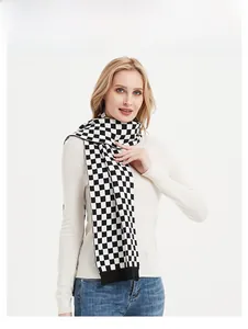 Detail of black and white checkerboard knit scarf with ribbed hem on model