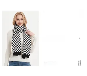 Detail of classic black and white checkered knit scarf paired with white sweater