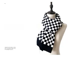 Detail of checkered knit scarf featuring black and white pattern with ribbed edges