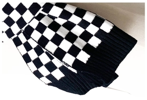 Detail of checkered knit scarf showing premium black and white weave and ribbed cuffs